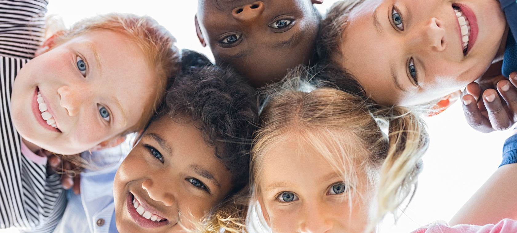 5 Kinder verschiedener Kulturen lächeln von oben in die Kamera 5 Kinder verschiedener Kulturen lächeln von oben in die Kamera